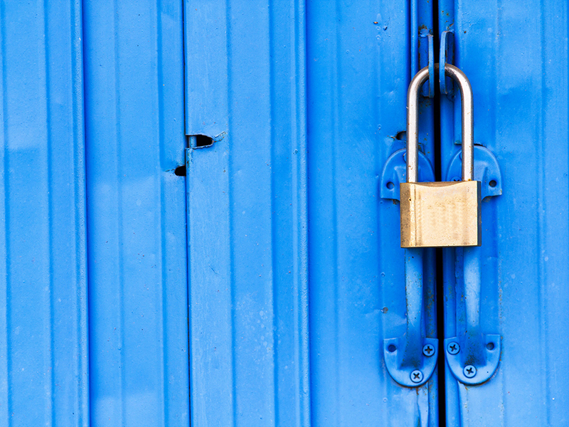 Photo of blue cargo container with pad lock connecting the doors