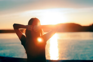 Woman ponders her future at a lake.