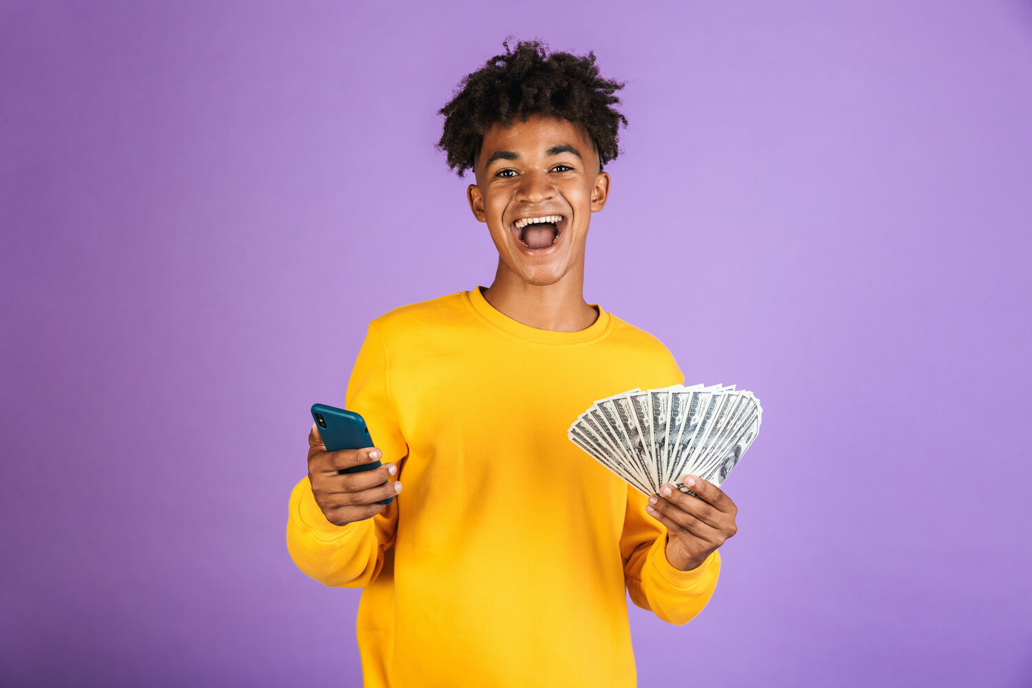 A young man holding cash and a smart phone
