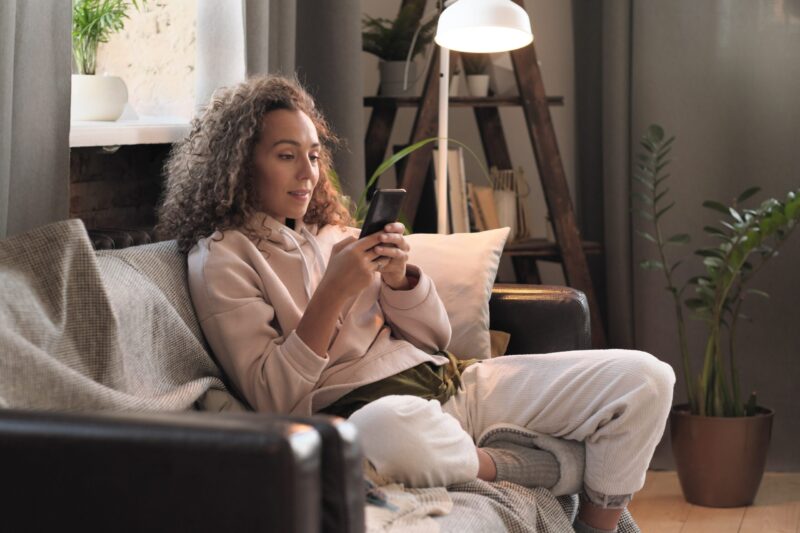 woman on couch using cell phone